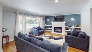Una sala de estar con chimenea, dos sofás, una mesa de centro y un televisor.