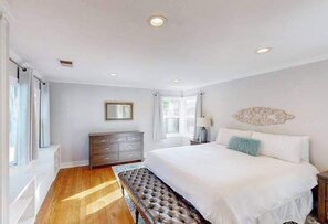 A bedroom with a large bed, a bench, a dresser, and a mirror. - Santa Rosa 2BR home with shaded patio — walk to Willi's Wine Bar (Santa Rosa)