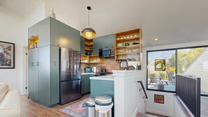 Une cuisine moderne équipée d’un réfrigérateur, d’un four à micro-ondes et d’une cuisinière intégrés. Un coin repas offre une vue sur l’extérieur.