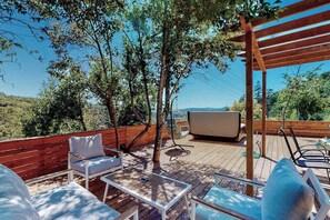 Una terraza exterior con una pérgola de madera, un sofá, una mesa y un televisor.