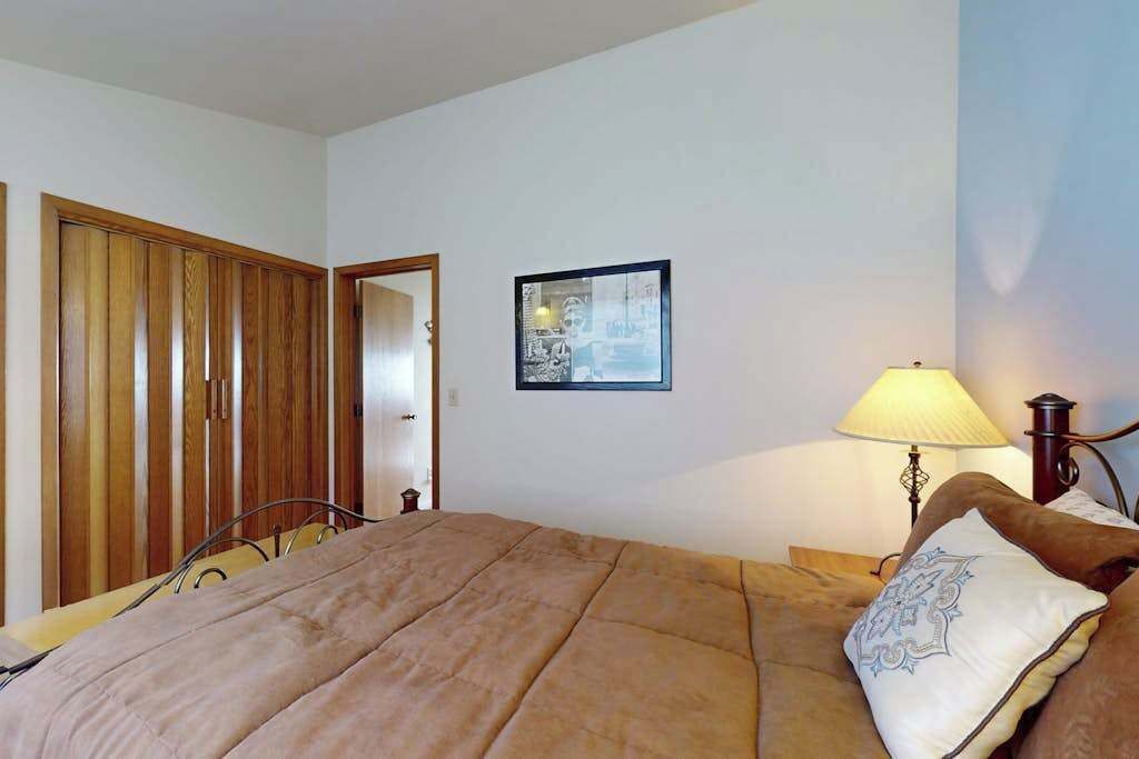 Una camera da letto con un letto, una lampada da comodino, un armadio in legno e un quadro appeso al muro.
