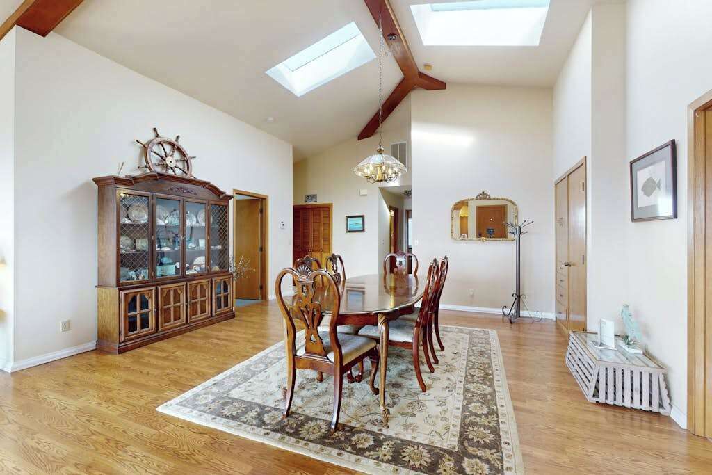 Un coin repas comprenant une table et des chaises en bois, un tapis à motifs et un buffet en bois doté de portes en verre.