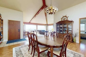 A dining area with a wooden table and chairs, a chandelier, and a wooden cabinet with glass doors. - Bodega Bay 3BR hilltop home with panoramic ocean views & wraparound deck (Bodega Bay)