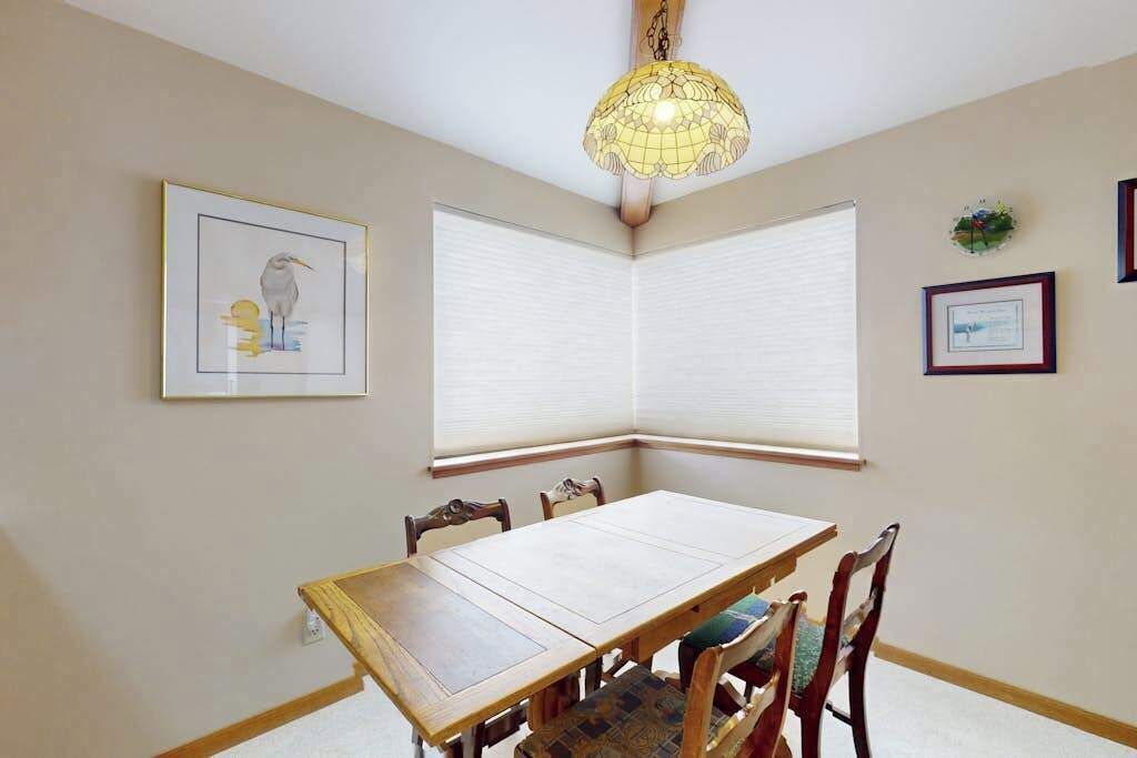 A dining area with a wooden table, chairs, a chandelier, and framed artwork on the walls.