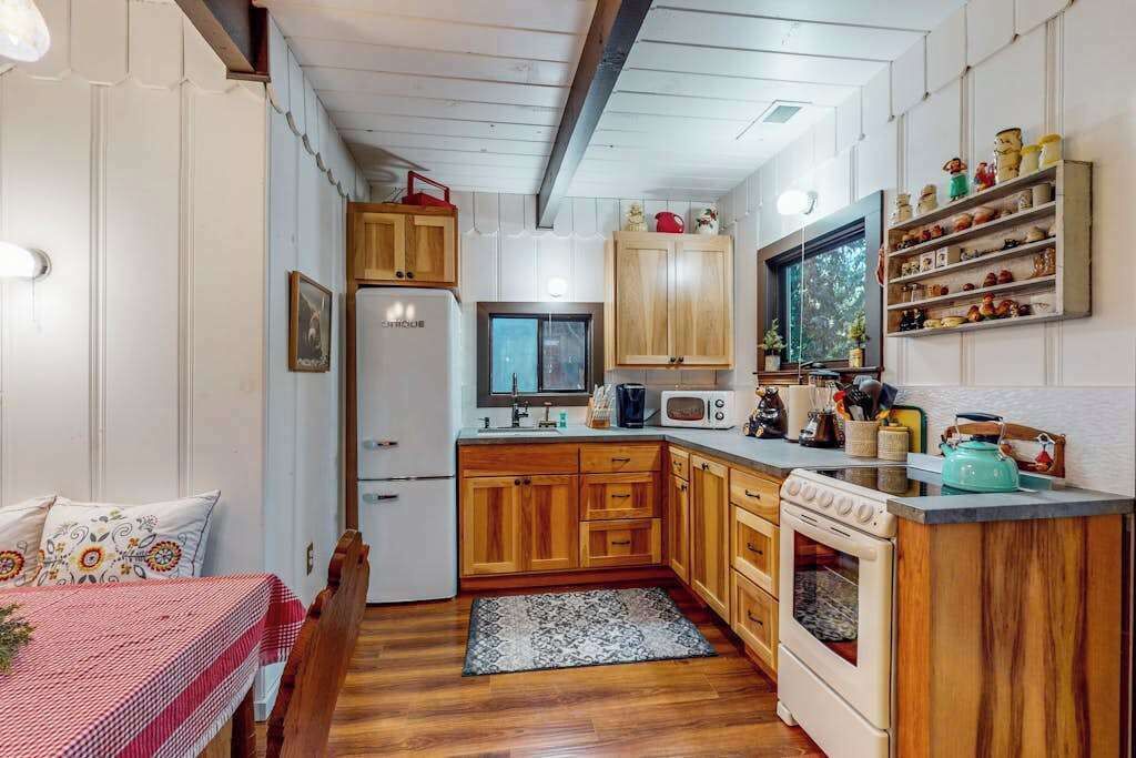 A compact kitchen with wooden cabinets, a refrigerator, a microwave, and a stove.