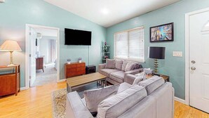 Ein Wohnzimmer mit Sofa, Couchtisch, Fernseher und Bildern an der Wand.