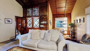 Ein Wohnzimmer mit weißem Sofa, Holzboden und Bücherregal.