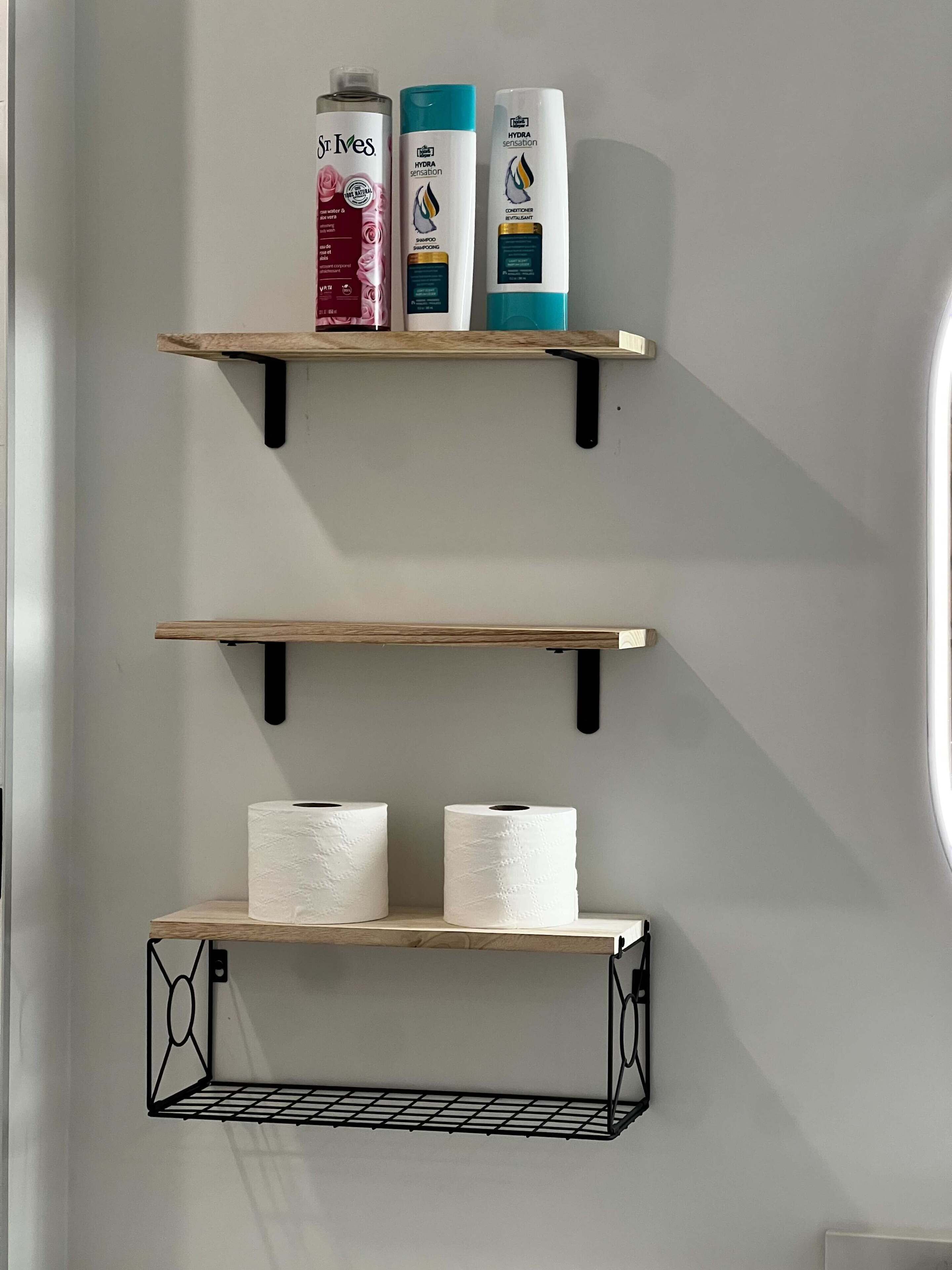 Three wooden shelves with toiletries and paper towels.