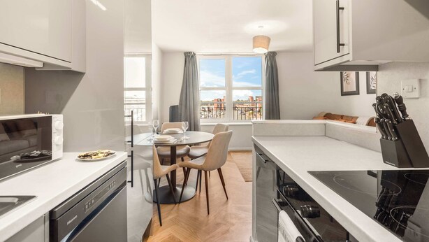 A modern kitchen with a dining area, a built-in oven, and a view of the city.