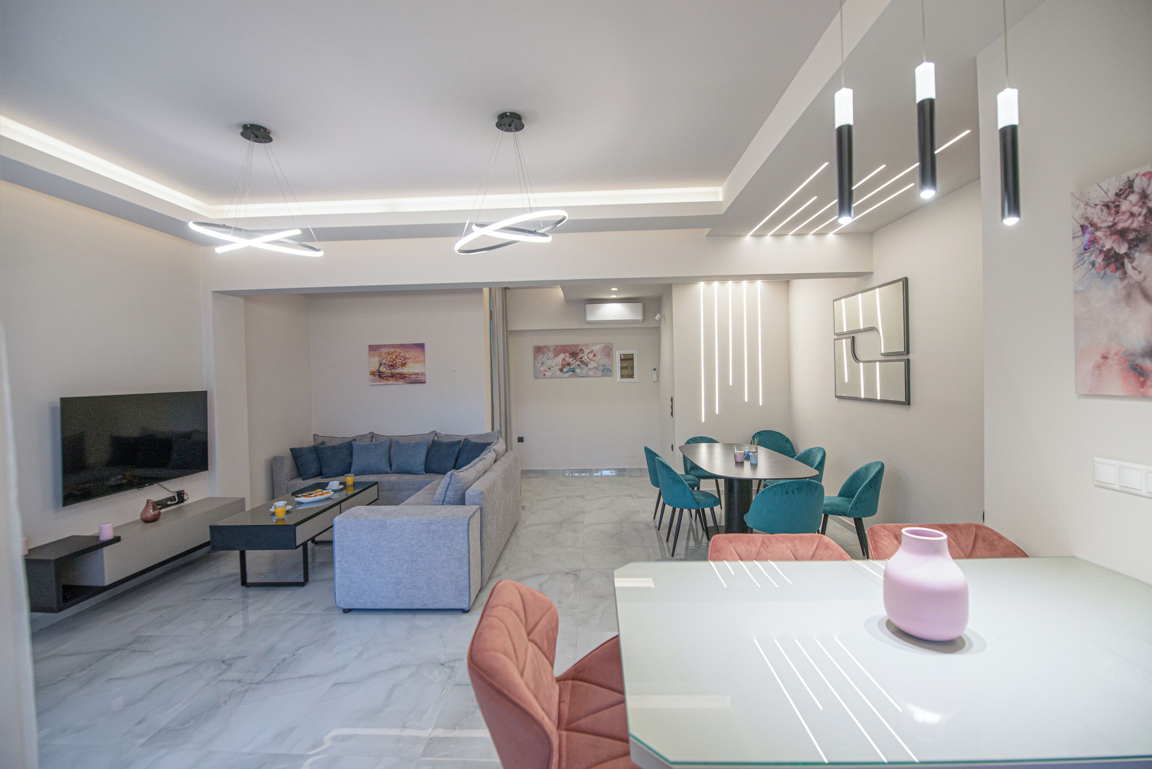 Un salon moderne doté d’un téléviseur à écran plat, d’un canapé, d’une table basse et d’un coin repas avec des chaises et une table.