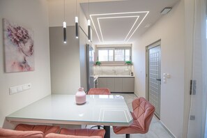 Ett modernt matområde med ett glasbord, rosa stolar och hängande lampor.