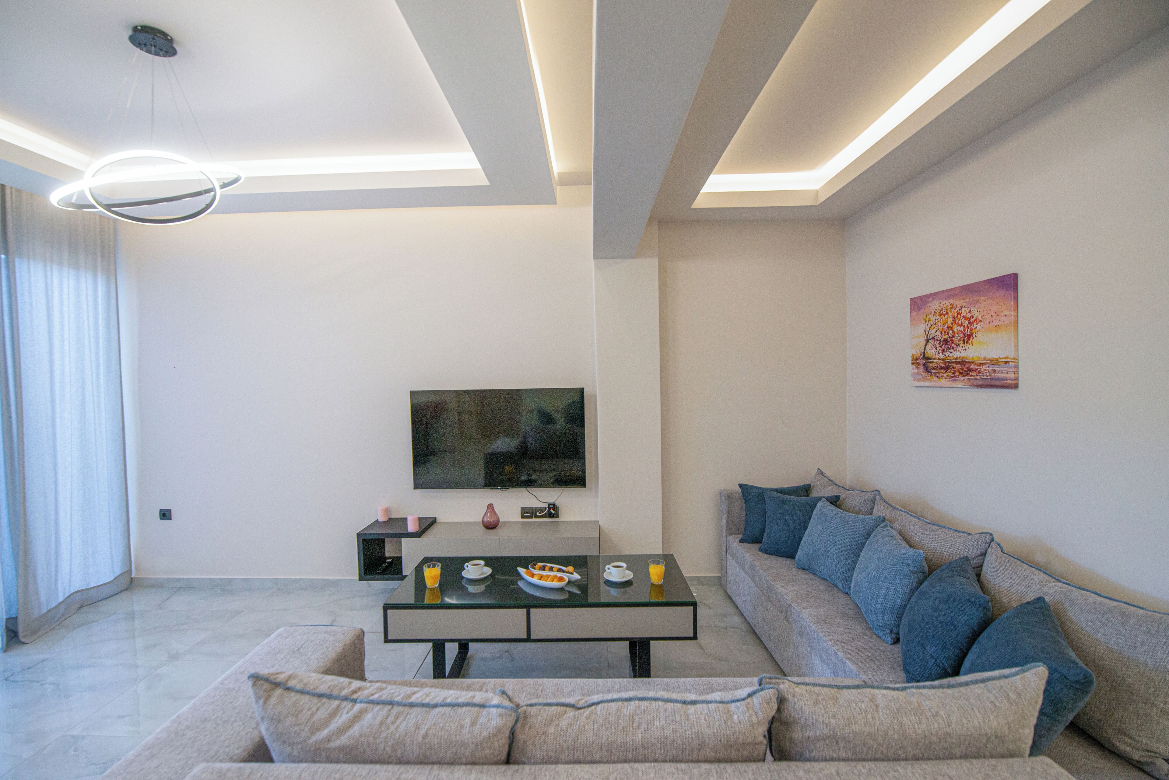 A modern living room with a sofa, a coffee table, and a TV.