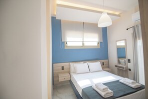 Une chambre d’hôtel moderne équipée d’un lit, de tables de chevet, d’une fenêtre avec stores, d’un miroir et d’un appareil de climatisation.