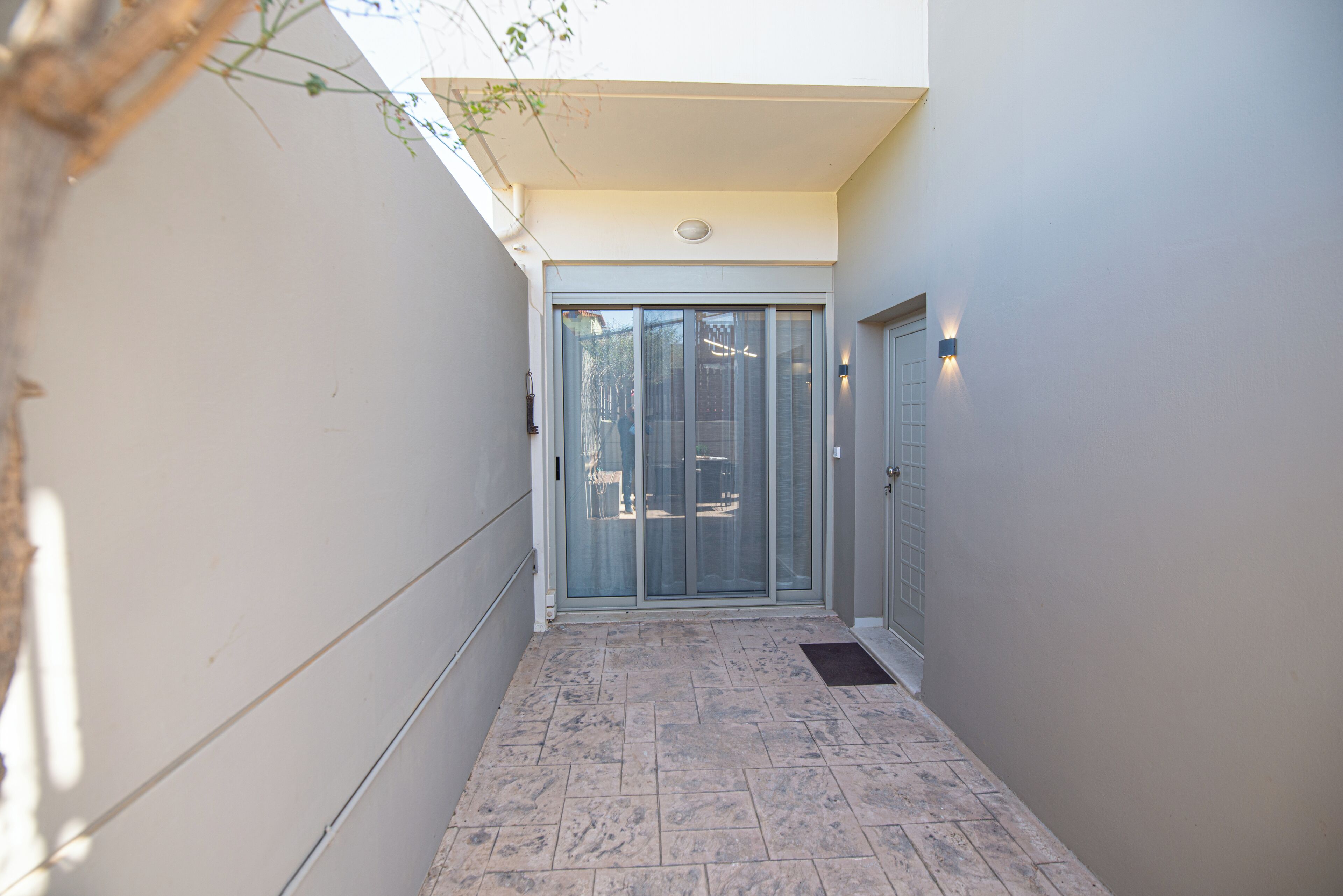 A narrow hallway with a sliding glass door leading to a room.