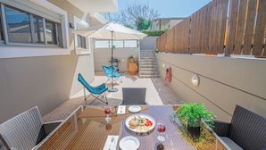 Eine Terrasse mit Esstisch, Gartenstühlen, einem Blumentopf und einem Holzzaun.