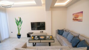 Ein modernes Wohnzimmer mit einer Couch, einem Couchtisch, einem Fernseher und einer Pflanze.