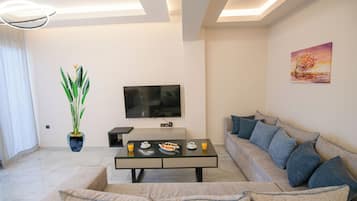 Un salon moderne avec un canapé, une table basse, un téléviseur et une plante.