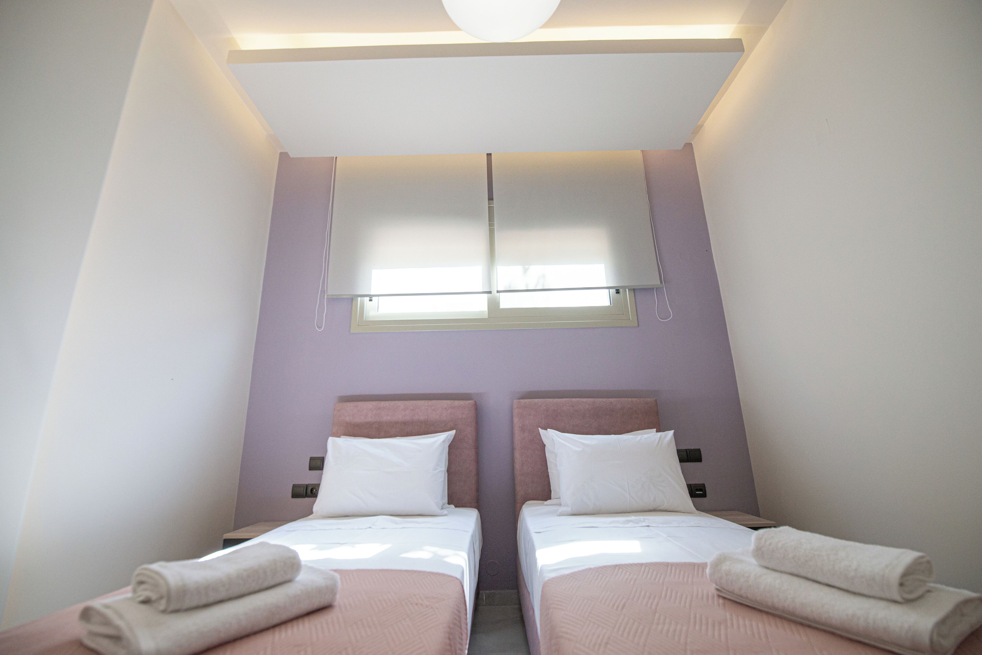 A twin room with two beds, a window, and a ceiling light.