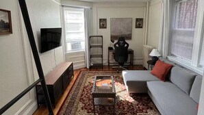 Ein Wohnzimmer mit einer Couch, einem Couchtisch, einem Fernseher, einer Treppe und einem gemusterten Teppich.
