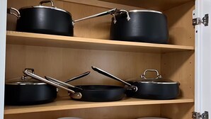 Eine Küchenschrank mit schwarzer Kochutensilien und gestapelten Tellern.