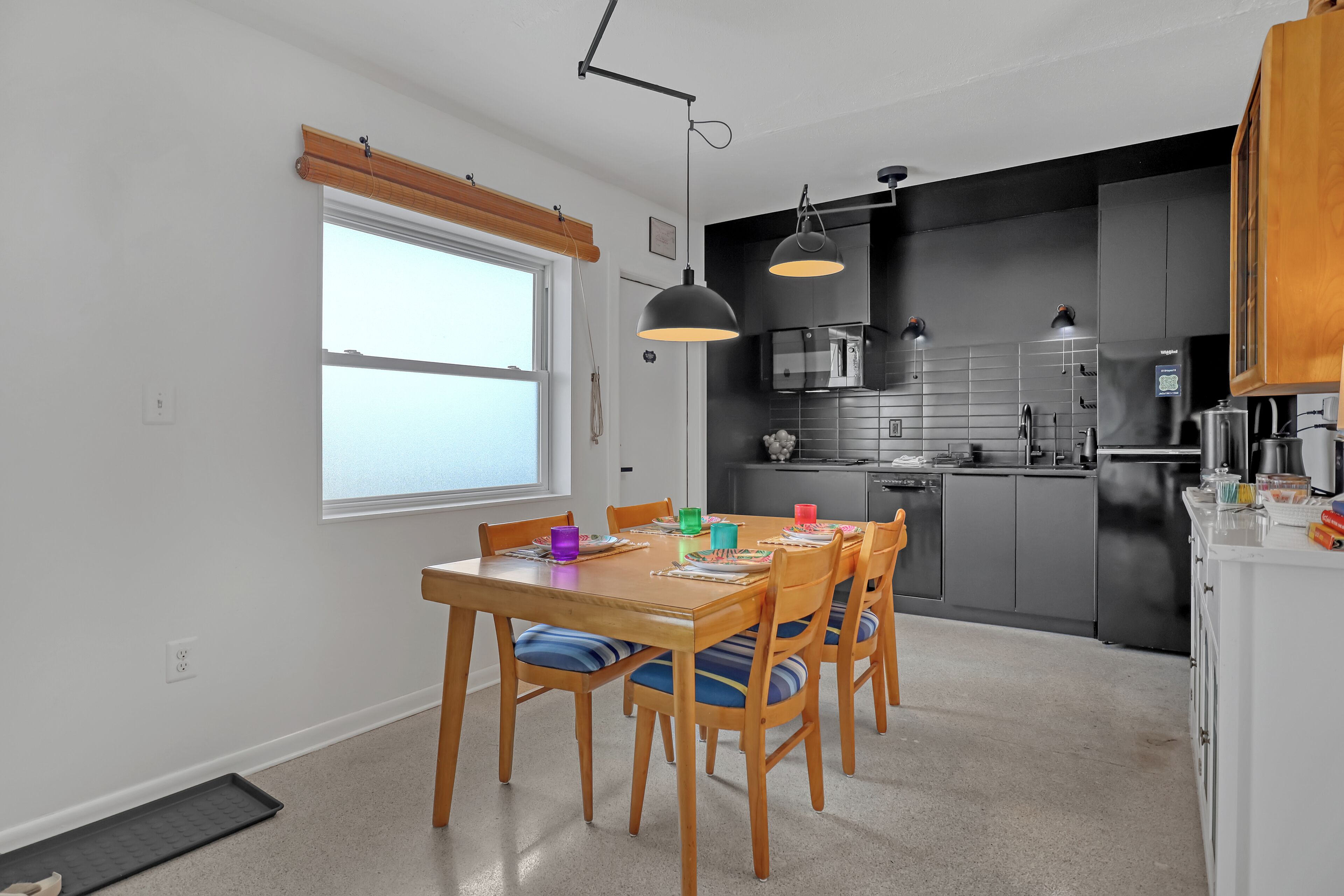 A modern kitchen with a dining table, chairs, and pendant lighting.