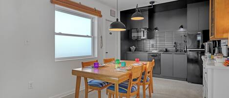 A modern kitchen with a dining table, chairs, and pendant lighting.