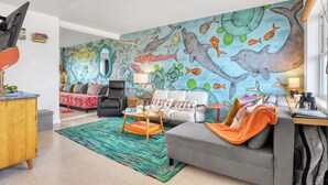 A living room with a mural of sea creatures, a sofa, a coffee table, and a TV. - UNIQUE Oceanside Escape 19 (Cocoa Beach)
