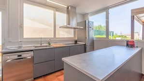 Una cocina moderna con lavavajillas, fregadero y un amplio ventanal.