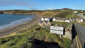 Una carretera costera con un cartel que indica la distancia a Aberdaron y Pwllheli.
