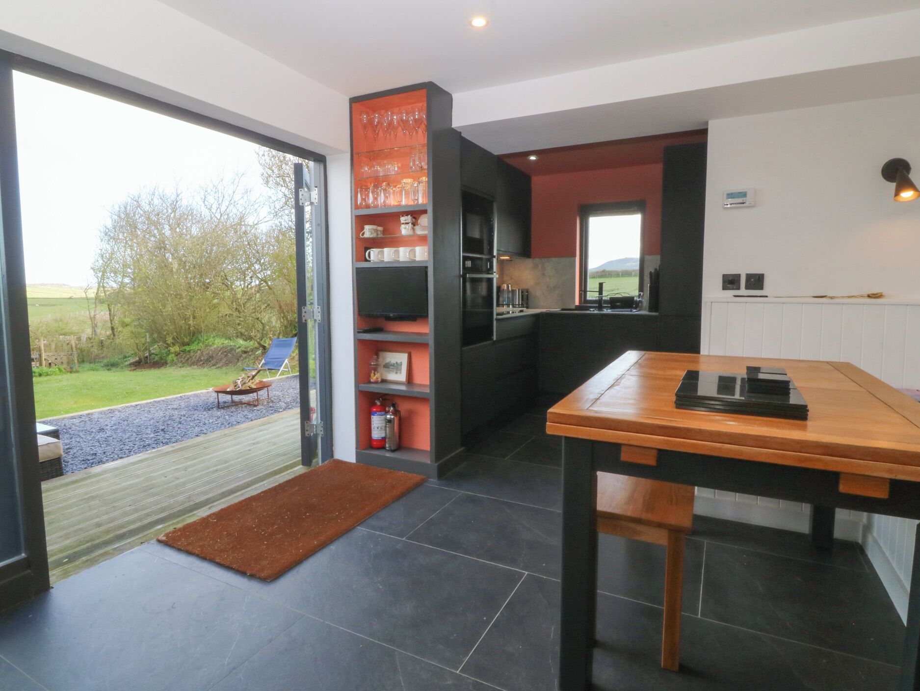 A modern kitchen with a dining area, a large window, and a view of the outdoors.