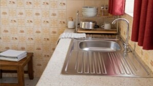 A kitchen with a stainless steel sink, wooden cabinets, and a tiled backsplash. - Mombasa:4 bedroom house :International chef ,tour guide.Perfect for family party (Mombasa)