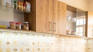 A kitchen with wooden cabinets, a tiled backsplash, and a water bottle on the counter. - Mombasa:4 bedroom house :International chef ,tour guide.Perfect for family party (Mombasa)