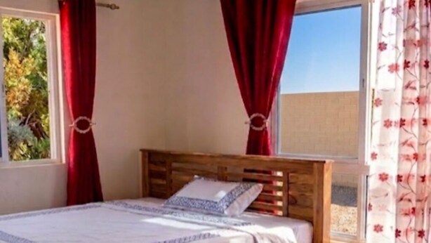 A room with a bed, a window with curtains, and a small table. - Mombasa:4 bedroom house :International chef ,tour guide.Perfect for family party (Mombasa)