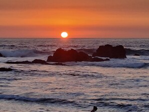 Ein Sonnenuntergang über dem Meer mit Wellen und Felsen.