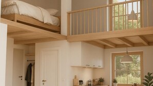 Een loft-achtige kamer met een stapelbed, een keukenhoek, een eettafel en een zithoek.