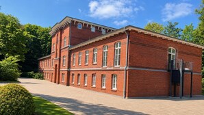 Een gebouw van rode baksteen met meerdere ramen en een overdekte ingang.