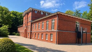 Ein roter Backsteinbau mit zahlreichen Fenstern und einem überdachten Eingang.