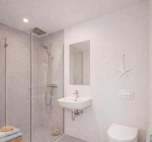 Ein modernes Badezimmer mit einer in Glas eingefassten Dusche, einem weißen Waschbecken, einer Toilette und einer Meerstern-Dekoration an der Wand.