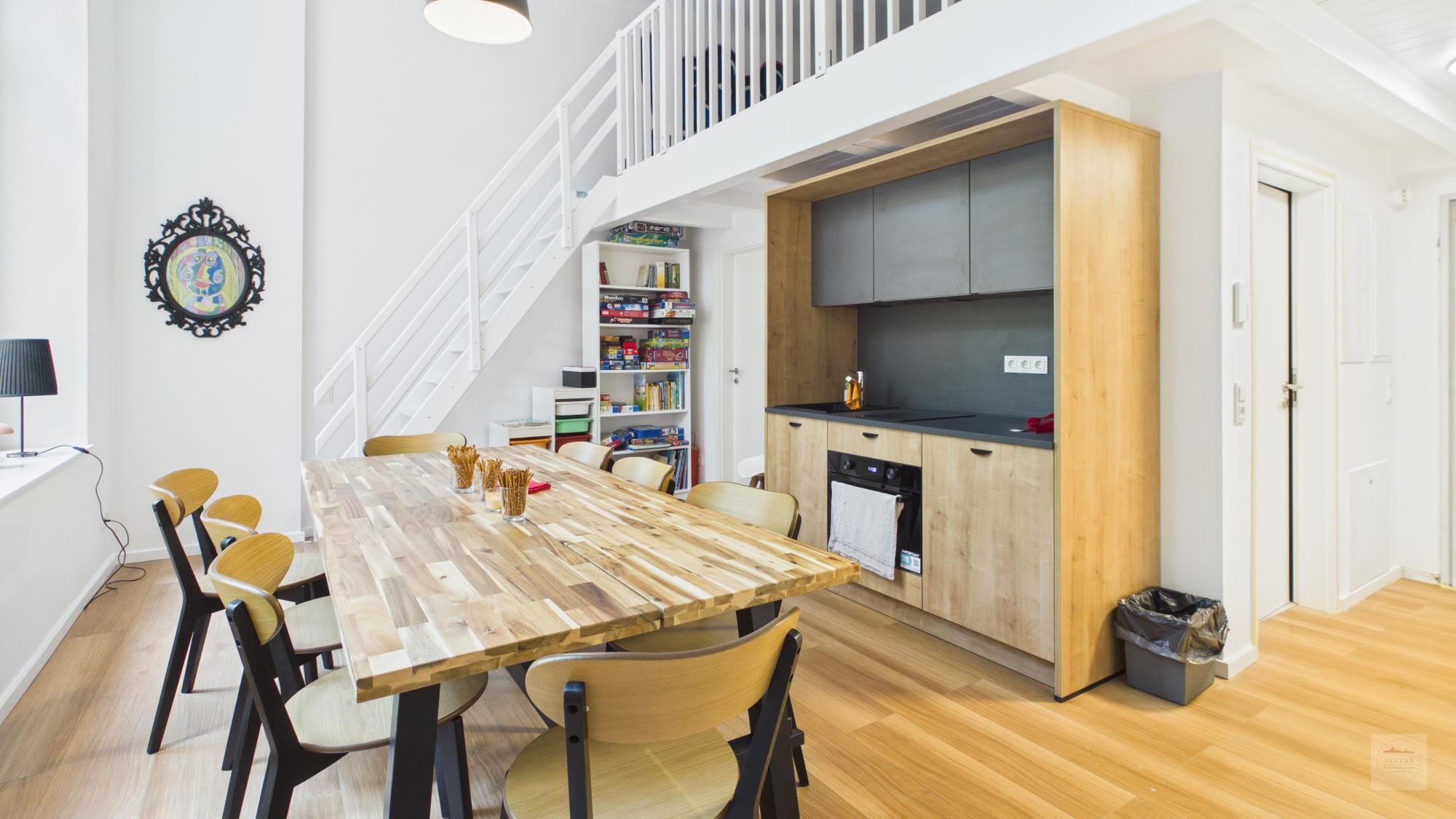 Eine moderne Küche mit Holzschränken, einer schwarzen Arbeitsplatte und einem eingebauten Backofen.