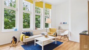 Een lichte woonkamer met een bank, salontafel en een schommelpaard.