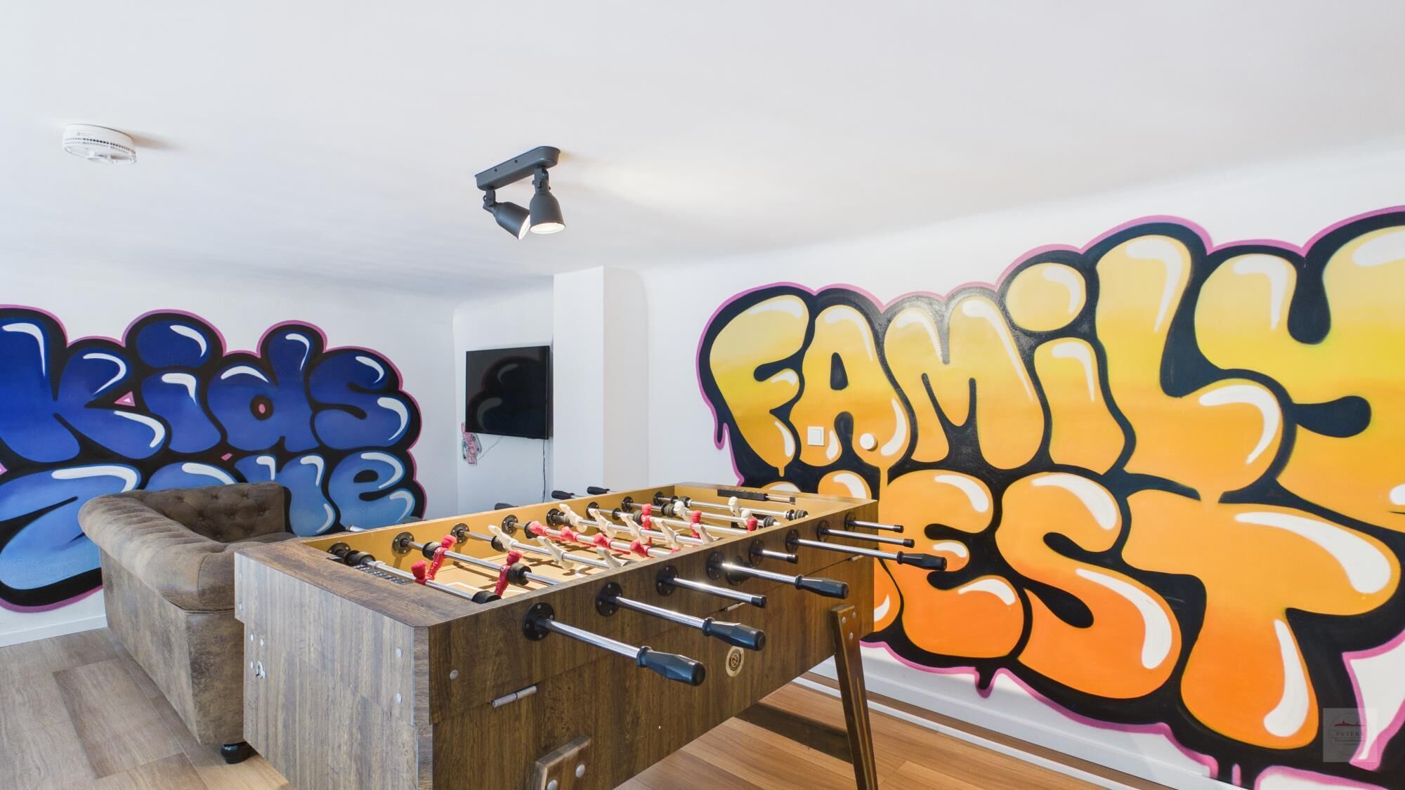 A room with a foosball table, a sofa, and graffiti art on the walls.