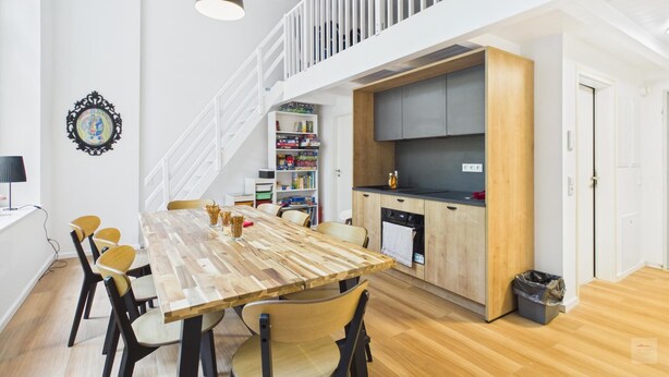 Une cuisine moderne avec des meubles en bois, un plan de travail noir et un four encastré.