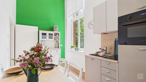Una cocina moderna con pared verde, armarios blancos, un lavabo y un reloj.