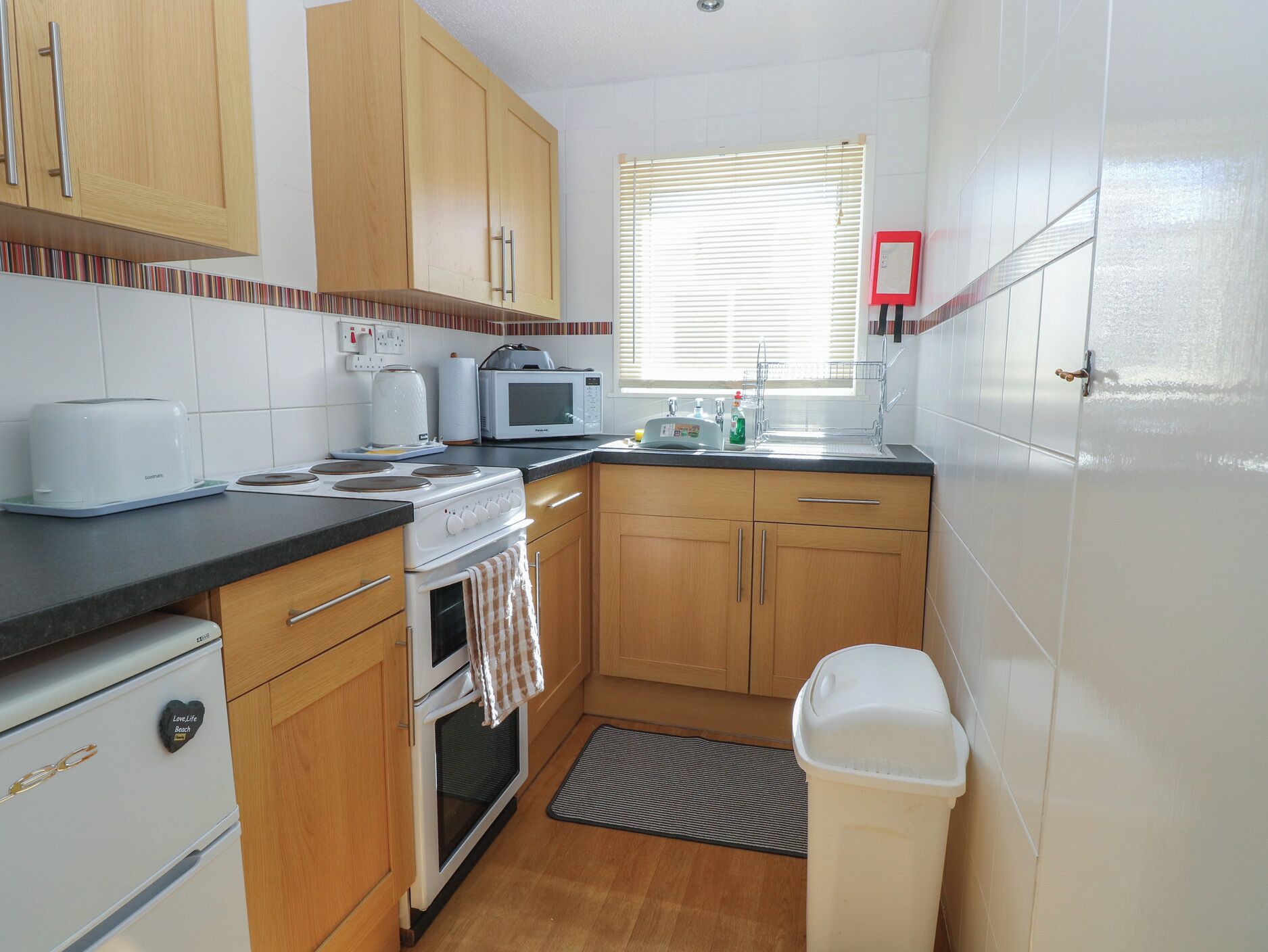 Una cocina con armarios de madera, microondas, tostadora y lavabo.