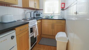 A kitchen with wooden cabinets, a microwave, a toaster, and a sink. - Mon Chalet (Great Yarmouth)