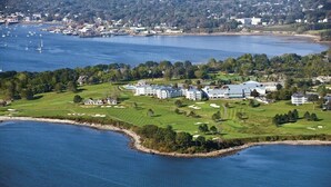 Eine Luftaufnahme eines Küstenresorts mit mehreren Gebäuden, einem Golfplatz und einer Marina.