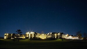 Ein mehrstöckiges Hotel mit Innenhof, beleuchteten Fenstern und sternenklarer Nacht.