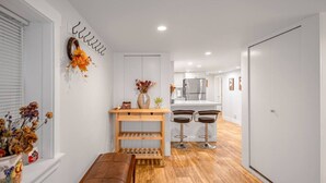 Una cocina moderna con una isla central, taburetes de bar y un banco de madera.