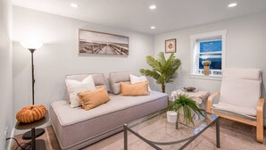 Una sala de estar moderna con un sofá, un sillón, una lámpara de pie y una mesa de centro de vidrio.