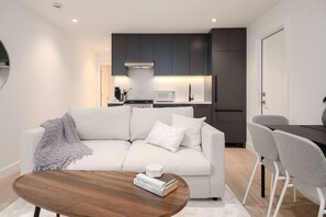 Uma sala de estar moderna com sofá, mesa de centro e espaço de jantar.